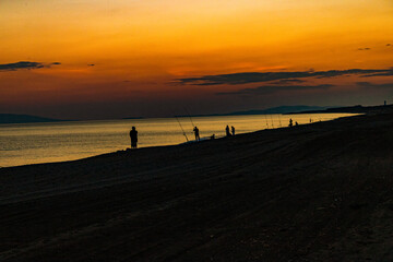 Fototapeta na wymiar sunset with fishermen on the beach
