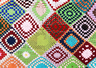 Beautiful multi colored plaid, knitted from squares. Granny squares are crocheted with red, yellow, green, purple, blue and orange yarn with different motifs. 