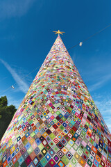 Huge Christmas tree created from knitted crocheted granny squares. They crocheted with red, yellow,...