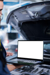Experienced serviceman in garage using mockup laptop to follow checklist while doing maintenance on...