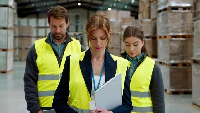 Team of warehouse employees standing in warehouse. Team of workers in reflective clothing in modern industrial factory, heavy industry, manufactrury.