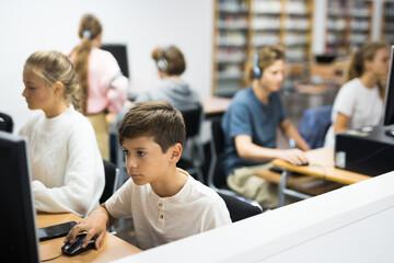 Preteen boy and girl learn to solve problems on computer in a school classroom