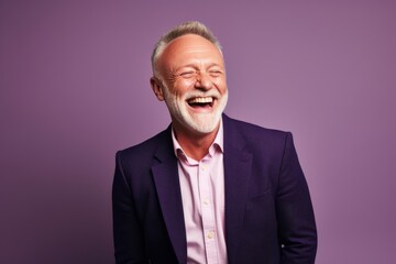 Portrait of a happy senior man laughing at the camera while standing against purple background.