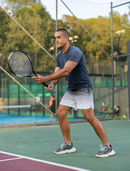 Focused man playing doubles tennis with female partners at warm sunny day, healthy lifestyle concept