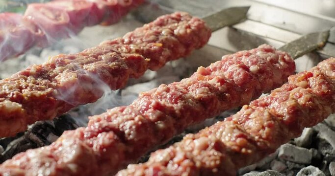 Adana kebab barbecue on charcoal grill. Traditional Turkish kebab grilled on skewers. Close-up