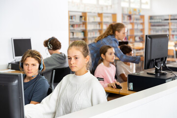 Active schoolchildren, preparing lessons in the classroom view the necessary information on the computer to write an abstract