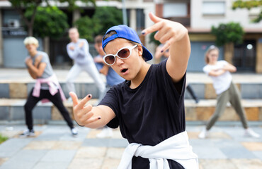 Portrait of emotional girl doing hip hop movements during group class at city street