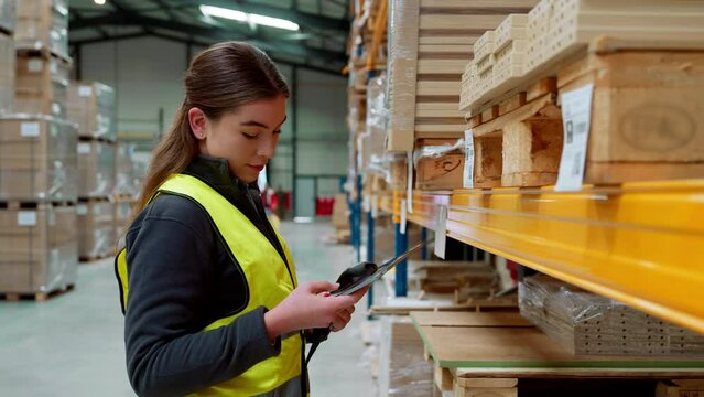 Female warehouse worker holding scanner, scanning the barcodes on products in warehouse. Warehouse manager using warehouse scanning system.