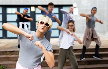 Fototapeta na wymiar Happy positive teenagers learn dance movements at city street