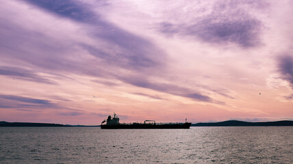 Obraz premium Silhouette of a large cargo ship in the sea at sunset