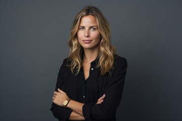 Portrait of a confident businesswoman standing with arms crossed against grey background