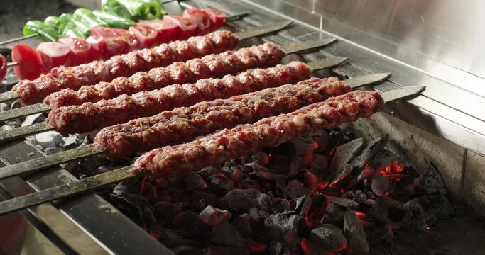 Adana kebab barbecue on charcoal grill. Meat and vegetables on grill. Traditional Turkish kebab grilled on skewers