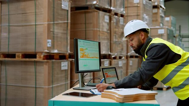 Warehouseman checking delivery, stock in warehouse on computer, pc. Warehouse manager using warehouse management software, app.