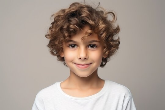 portrait of a cute little boy with curly hair over grey background