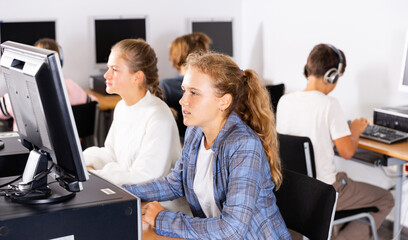 Group of young girls and boys sitting in computer classroom and exercising.