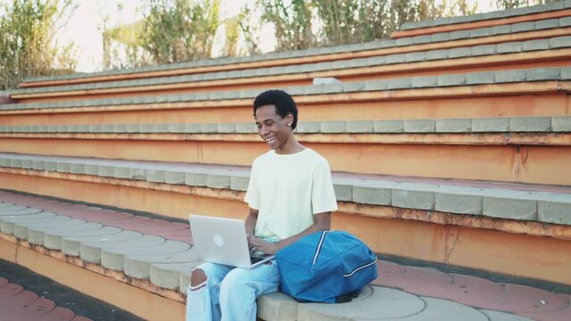 Cheerful non-binary student greeting his university classmate on a video call. Young transgender student studying online at a distance with classmates. Gender equality and gender expression. 