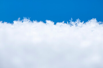 Snowy surface with empty blue and white space for text. Crystal snowflakes on white snow close-up....