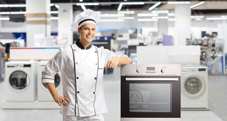 Young male chef leaning on an oven