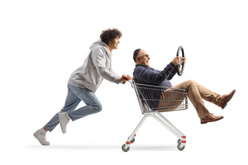 Young man running and pushing a mature man with a steering wheel in a shopping cart