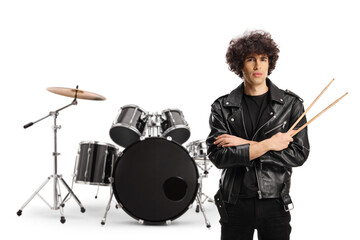 Young male drummer standing and holding a pair of drumsticks in front of drums