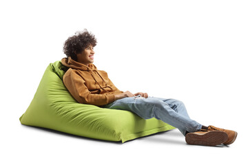 Gen z guy sitting on a green bean bag chair and smiling