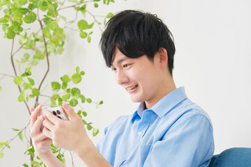自宅でスマートフォンで動画を見る男性