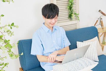 自宅でノートパソコンで動画を見る男性