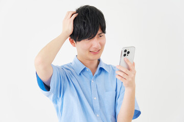 Fototapeta premium 頭を抱えながらスマートフォンを見る男性 白背景