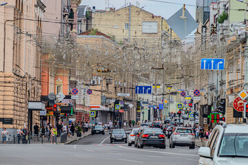 Fototapeta premium Old european early morning city. The streets of a European town. Urban traffic cars and people driving around the city. Kharkiv, Ukraine 07-07-2023
