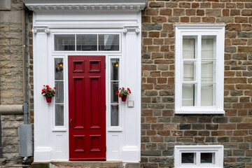 A vibrant red solid front door to a house. The exterior wall is brown brick with multiple closed...