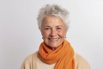 Portrait of smiling senior woman in orange scarf on white background.