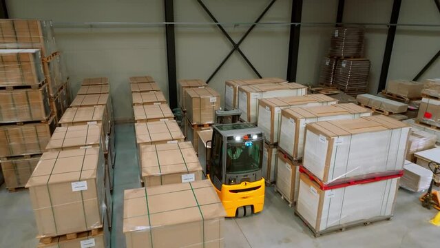 Top view of warehouse worker driving forklift. Warehouse worker preparing products for shipmennt, delivery, checking stock in warehouse.