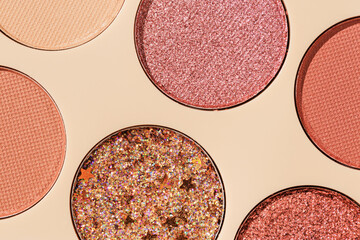 Close up minimal pattern with colorful eye shadow samples, trend color swatches on beige background. Eyeshadows powder with glitters for makeup, shiny and matte, aesthetic photo, top view