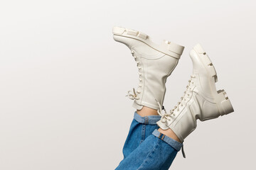 Female legs in white combat boots and blue jeans upside down on white background, side view. Woman...