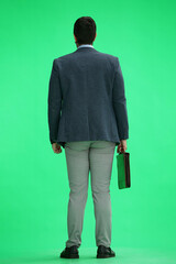 A man in an office suit with a briefcase on a green background, back view