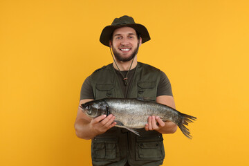Fisherman with caught fish on yellow background