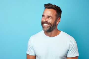 Portrait of a handsome man laughing and looking at camera against blue background