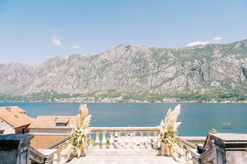 Wedding semi-arch attached to the balustrade of an ancient staircase overlooking the sea and mountains