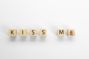 Wooden cubes with phrase Kiss Me on white background, flat lay
