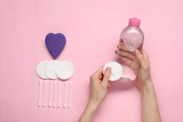 Woman with makeup remover, cotton pads, buds and sponge on pink background, top view