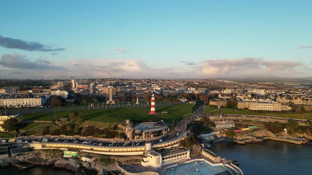 Cinematic aerial view of Plymouth, England at the sunset. Drone view of Smeaton's tower, Hoe Park, Plymouth Harbour during holden hour. 
