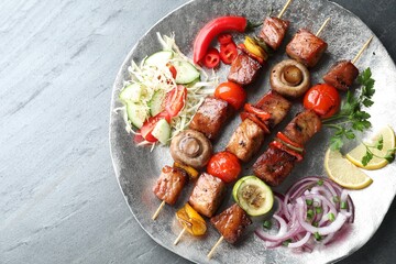 Delicious shish kebabs with vegetables on grey textured table, top view. Space for text
