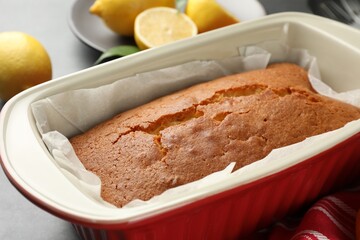 Tasty lemon cake in baking dish on table, closeup
