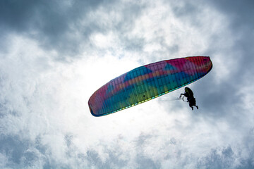 A person paragliding in the sky with a colorful parachute and safety harness.Mountains, Extreme...