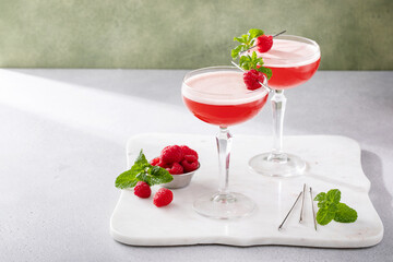 Raspberry martini in coupe glasses garnished with fresh raspberries and mint