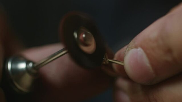 Extreme close up - a jeweler polishes a precious stone in a newly created ring