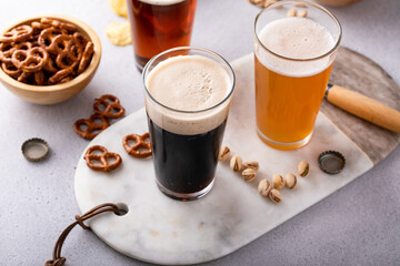 Dark stout, lager and ale beer in tall glasses on the table with snacks