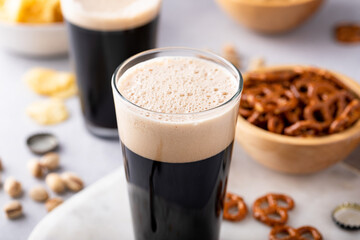 Dark stout beer in tall glasses with snacks