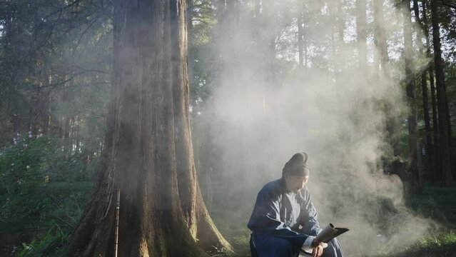 people in ancient costume reading book in forest