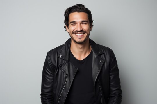 Portrait of handsome young man in black leather jacket, smiling at camera.